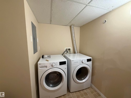 Laundry area with a paneled ceiling, electric panel, washer and clothes dryer, and light floors - 321 4304 139 Avenue, Edmonton, AB - Indoor Photo Showing Laundry Room