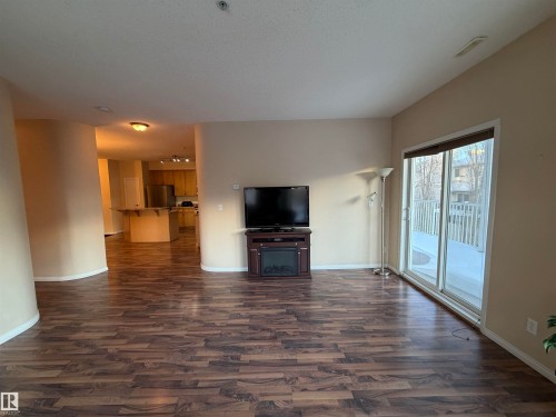 Unfurnished living room featuring dark wood-type flooring and a fireplace - 321 4304 139 Avenue, Edmonton, AB - Indoor