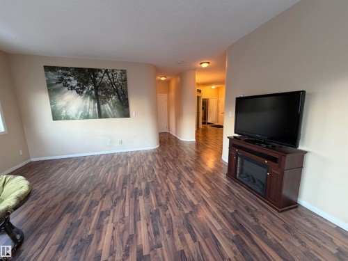 Unfurnished living room featuring dark wood-style flooring and a glass covered fireplace - 321 4304 139 Avenue, Edmonton, AB - Indoor Photo Showing Living Room