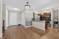 Kitchen with stainless steel appliances, a peninsula, backsplash, light wood-type flooring, and dark stone counters - 