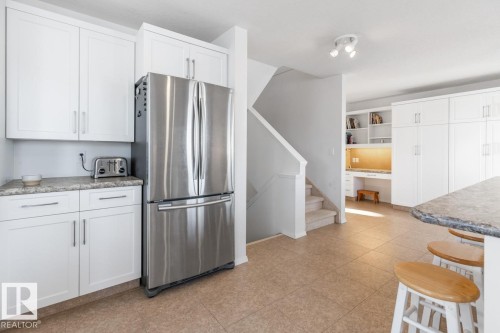 Kitchen with built in study area, freestanding refrigerator, white cabinets, open shelves, and a breakfast bar - 6508 109 Avenue, Edmonton, AB - Indoor Photo Showing Kitchen