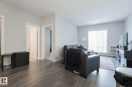 Living area featuring dark wood-type flooring, a baseboard heating unit, and an AC wall unit - 407 812 Welsh Drive, Edmonton, AB - Indoor Photo Showing Living Room