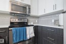 Kitchen with stainless steel appliances, tasteful backsplash, and white cabinetry - 407 812 Welsh Drive, Edmonton, AB  - Indoor Photo Showing Kitchen With Upgraded Kitchen 