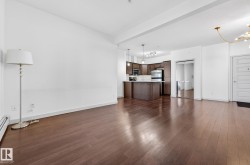 Unfurnished living room with a chandelier, dark wood-style flooring, and a baseboard heating unit - 