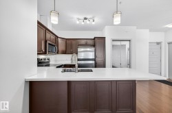 Kitchen with dark brown cabinets, hanging light fixtures, stainless steel appliances, tasteful backsplash, and a peninsula - 