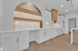 Kitchen with white cabinets, parquet floors, light stone countertops, recessed lighting, and backsplash - 