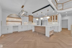 Kitchen with glass fronted cabinets, white cabinetry, parquet flooring, and suspended lighting - 