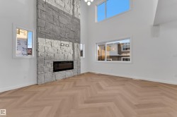 Unfurnished living room with a high ceiling and a stone fireplace - 