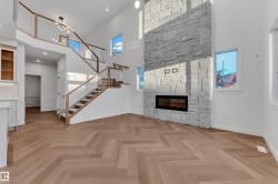 Unfurnished living room featuring a high ceiling, a fireplace, stairs, and plenty of natural light - 