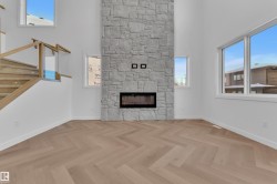 Unfurnished living room with a high ceiling, a stone fireplace, and stairway - 