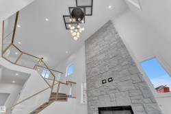 Detailed view of a stone fireplace, recessed lighting, and a chandelier - 