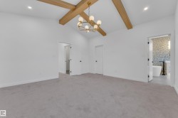 Unfurnished bedroom featuring light colored carpet, a chandelier, recessed lighting, and connected bathroom - 