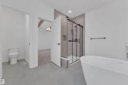Bathroom featuring a soaking tub, a chandelier, a shower stall, and finished concrete floors - 