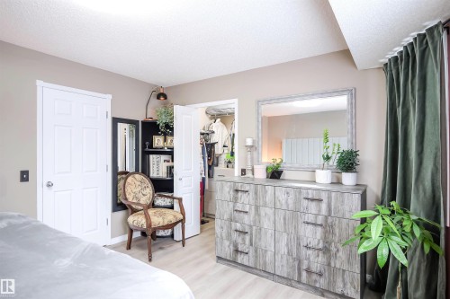 Bedroom featuring a spacious closet, a textured ceiling, and light wood finished floors - 5836 204 Street, Edmonton, AB - Indoor Photo Showing Bedroom