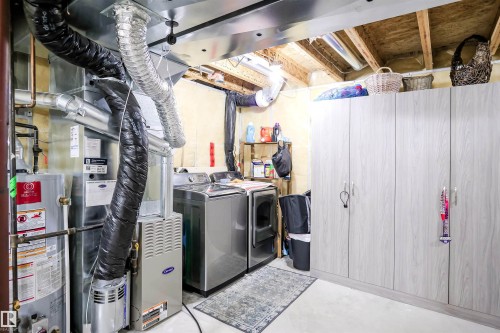 Washroom with gas water heater, concrete flooring, and washer and clothes dryer - 5836 204 Street, Edmonton, AB - Indoor Photo Showing Laundry Room