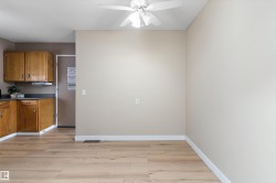 Kitchen featuring dark countertops, brown cabinetry, light wood-style floors, and a ceiling fan - 