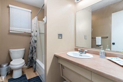 Full bath with vanity, shower / bath combination with curtain, light wood-style floors, and a textured ceiling - 17107 86 Avenue Nw, Edmonton, AB - Indoor Photo Showing Bathroom
