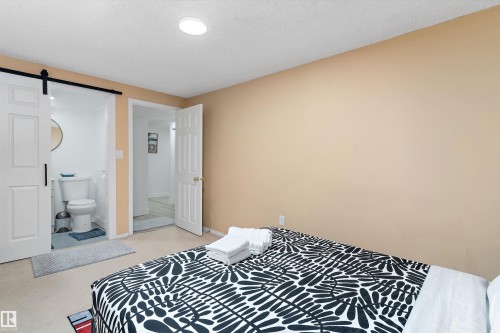 Bedroom with a barn door, connected bathroom, and a textured ceiling - 17107 86 Avenue Nw, Edmonton, AB - Indoor Photo Showing Bedroom