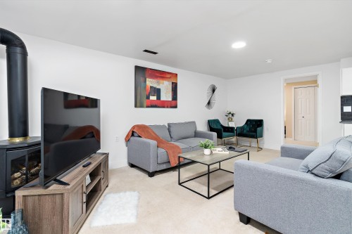 Living room featuring a wood stove and light carpet - 17107 86 Avenue Nw, Edmonton, AB - Indoor Photo Showing Living Room