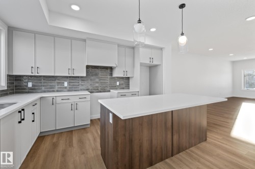 Kitchen featuring white cabinetry, backsplash, a kitchen island, decorative light fixtures, and recessed lighting - 206 Starling, Fort Saskatchewan, AB - Indoor Photo Showing Kitchen With Upgraded Kitchen
