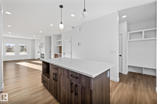 Kitchen with dark brown cabinetry, recessed lighting, a center island, hanging light fixtures, and light wood-style floors - 206 Starling, Fort Saskatchewan, AB - Indoor