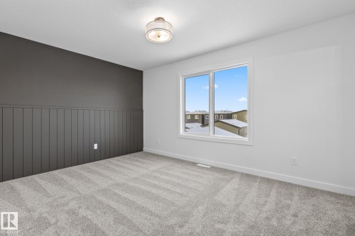 Carpeted spare room featuring wainscoting - 206 Starling, Fort Saskatchewan, AB - Indoor Photo Showing Other Room