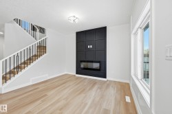 Unfurnished living room featuring stairway, light wood-style floors, and a fireplace - 
