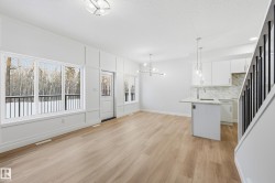 Kitchen with white cabinetry, a chandelier, light wood-type flooring, decorative light fixtures, and backsplash - 