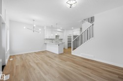 Unfurnished living room featuring stairway, a chandelier, and light wood-style flooring - 