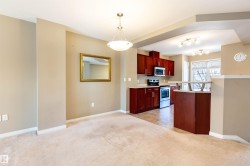 Kitchen with light countertops, stainless steel appliances, decorative light fixtures, light carpet, and dark brown cabinets - 