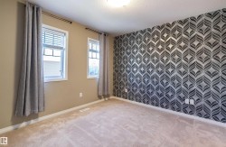 Carpeted primary room with an accent wall, wallpapered walls, and a textured ceiling - 