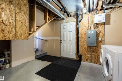 Unfinished below grade area featuring electric panel and washer and clothes dryer - 