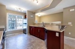 Kitchen with a peninsula, light countertops, stainless steel appliances, and reddish brown cabinets - 