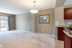 Kitchen featuring light countertops, hanging light fixtures, and light colored carpet - 