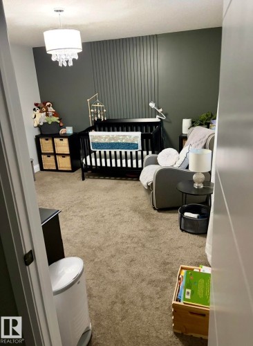 Bedroom featuring light colored carpet, a nursery area, and an accent wall - 25 Harrison Gate, Spruce Grove, AB - Indoor Photo Showing Other Room