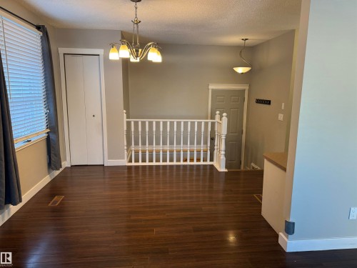 Unfurnished dining area with dark wood-type flooring, a textured ceiling, and a chandelier - 21 Lundy Park Road, Stony Plain, AB - Indoor Photo Showing Other Room