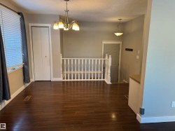 Unfurnished dining area with dark wood-type flooring, a textured ceiling, and a chandelier - 