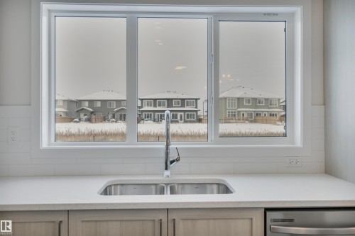 Kitchen featuring light stone counters, a residential view, and dishwasher - 5742 Hawthorn Common, Edmonton, AB - Indoor Photo Showing Kitchen With Double Sink