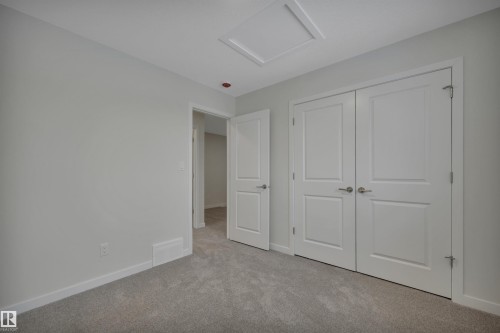 Unfurnished bedroom featuring attic access, carpet, and a closet - 5742 Hawthorn Common, Edmonton, AB - Indoor Photo Showing Other Room