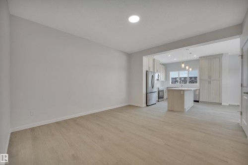 Kitchen featuring a kitchen island, light wood-type flooring, light countertops, light brown cabinetry, and appliances with stainless steel finishes - 5742 Hawthorn Common, Edmonton, AB - Indoor