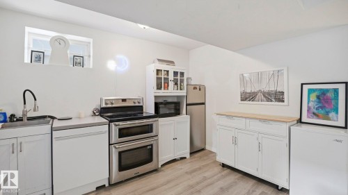 Kitchen featuring white cabinetry, stainless steel appliances, and light wood finished floors - 9831 83 Avenue, Edmonton, AB - Indoor Photo Showing Kitchen