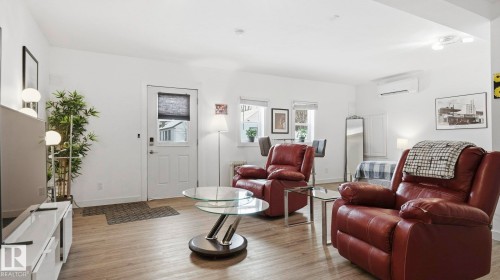 Living room with light wood-style floors and a wall unit AC - 9831 83 Avenue, Edmonton, AB - Indoor Photo Showing Living Room