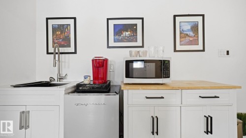 Bar area with white cabinetry, white microwave, and butcher block countertops - 9831 83 Avenue, Edmonton, AB - Indoor