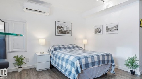 Bedroom with wood finished floors and a wall unit AC - 9831 83 Avenue, Edmonton, AB - Indoor Photo Showing Bedroom
