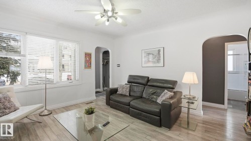 Living room with arched walkways, a textured ceiling, light wood-style floors, and ceiling fan - 9831 83 Avenue, Edmonton, AB - Indoor Photo Showing Living Room
