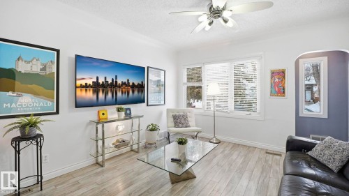 Living area featuring light wood-style floors, a textured ceiling, and a ceiling fan - 9831 83 Avenue, Edmonton, AB - Indoor Photo Showing Living Room