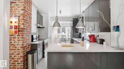 Kitchen featuring hanging light fixtures, appliances with stainless steel finishes, backsplash, a peninsula, and a breakfast bar - 9831 83 Avenue, Edmonton, AB - Indoor Photo Showing Kitchen With Upgraded Kitchen