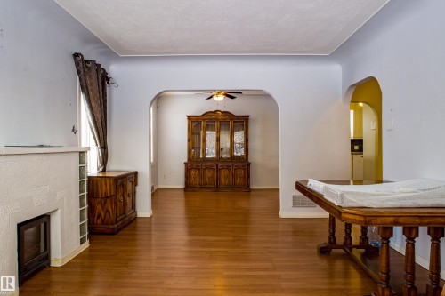 Foyer entrance featuring wood finished floors, a glass covered fireplace, arched walkways, and ceiling fan - 9228 124A Avenue, Edmonton, AB - Indoor With Fireplace