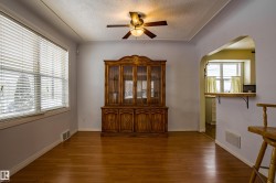 Unfurnished dining area featuring dark wood-style floors, arched walkways, ceiling fan, and a textured ceiling - 