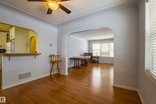 Empty room with a textured ceiling, arched walkways, wood finished floors, and a ceiling fan - 9228 124A Avenue, Edmonton, AB - Indoor